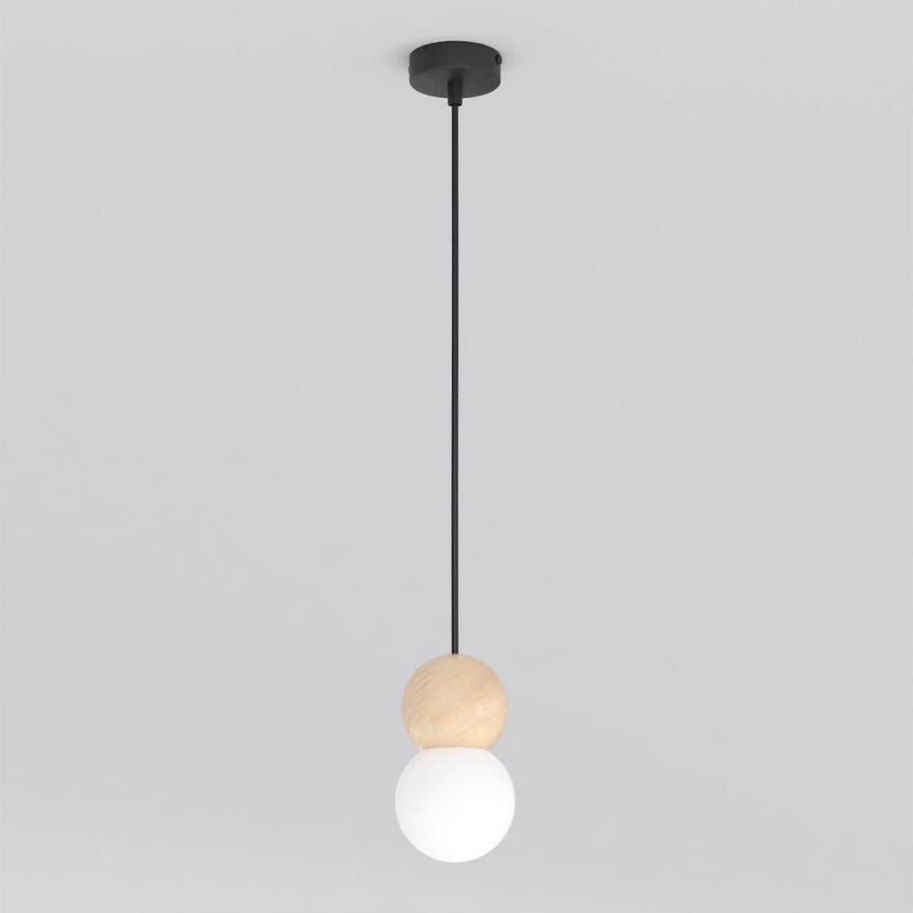 Zwarte hanglamp met houten bol en witte glazen kap aan een dun zwart snoer, tegen een lichtgrijze achtergrond