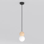 Zwarte hanglamp met houten bol en witte glazen kap aan een dun zwart snoer, tegen een lichtgrijze achtergrond