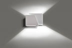 Witte moderne wandlamp van twee verschoven vlakken die licht naar boven en beneden over de muur werpt
