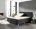 Crèmekleurige splittopper op een antracietkleurige boxspring met één verstelde bedhelft in een moderne slaapkamer
