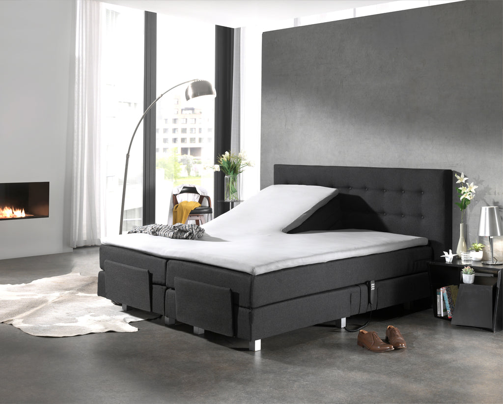 Wit splittopper hoeslaken op een antracietkleurige elektrische boxspring met opgeklapt hoofdeinde in een moderne slaapkamer