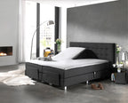 Wit splittopper hoeslaken op een antracietkleurige elektrische boxspring met opgeklapt hoofdeinde in een moderne slaapkamer