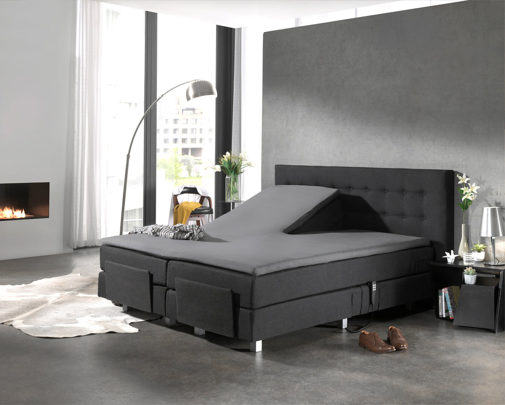 Grijs hoeslaken op een splittopper van een boxspring met antraciet hoofdbord, één helft omhoog gesteld