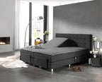 Grijs hoeslaken op een splittopper van een boxspring met antraciet hoofdbord, één helft omhoog gesteld