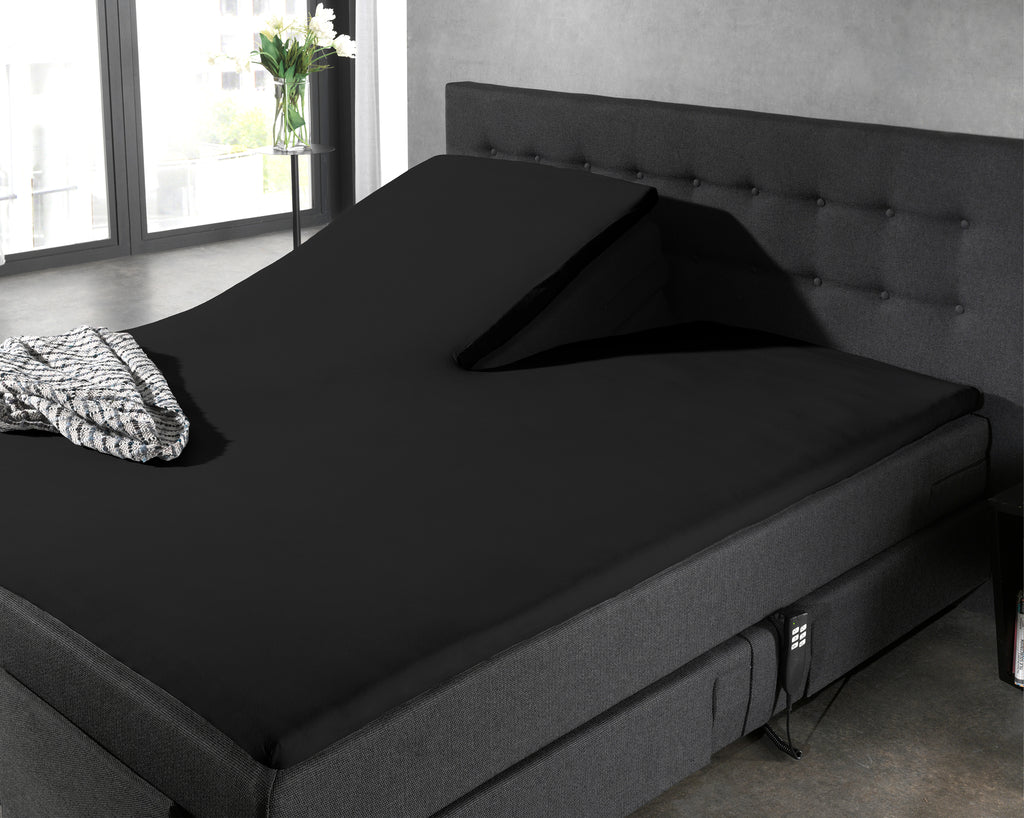 Zwart hoeslaken op een splittopper van een donkergrijs boxspringbed, met één opgetilde topperhelft