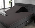 Antraciet splittopper hoeslaken op een boxspring met opgestelde split bij het hoofdeinde