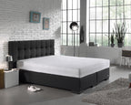 Wit molton hoeslaken op een matras met donkergrijs boxspringbed en gecapitonneerd hoofdbord in een slaapkamer