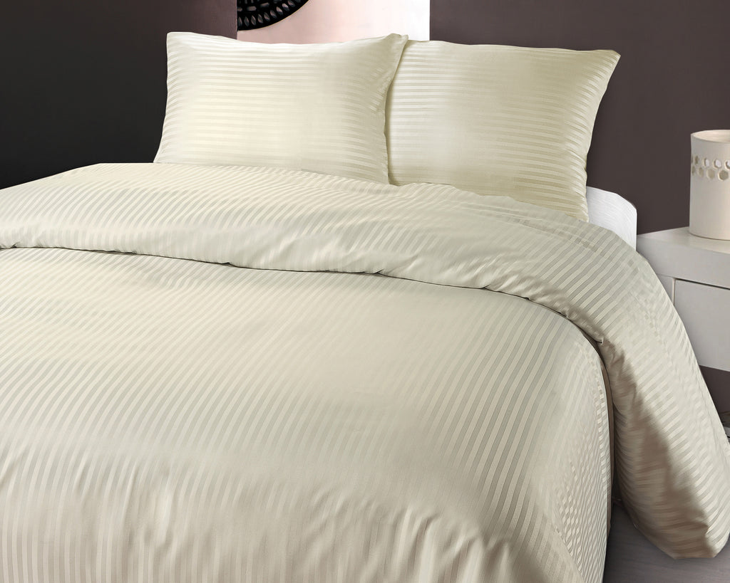 Opgemaakt bed met crèmekleurig dekbedovertrek met hotelstreep en twee bijpassende kussens