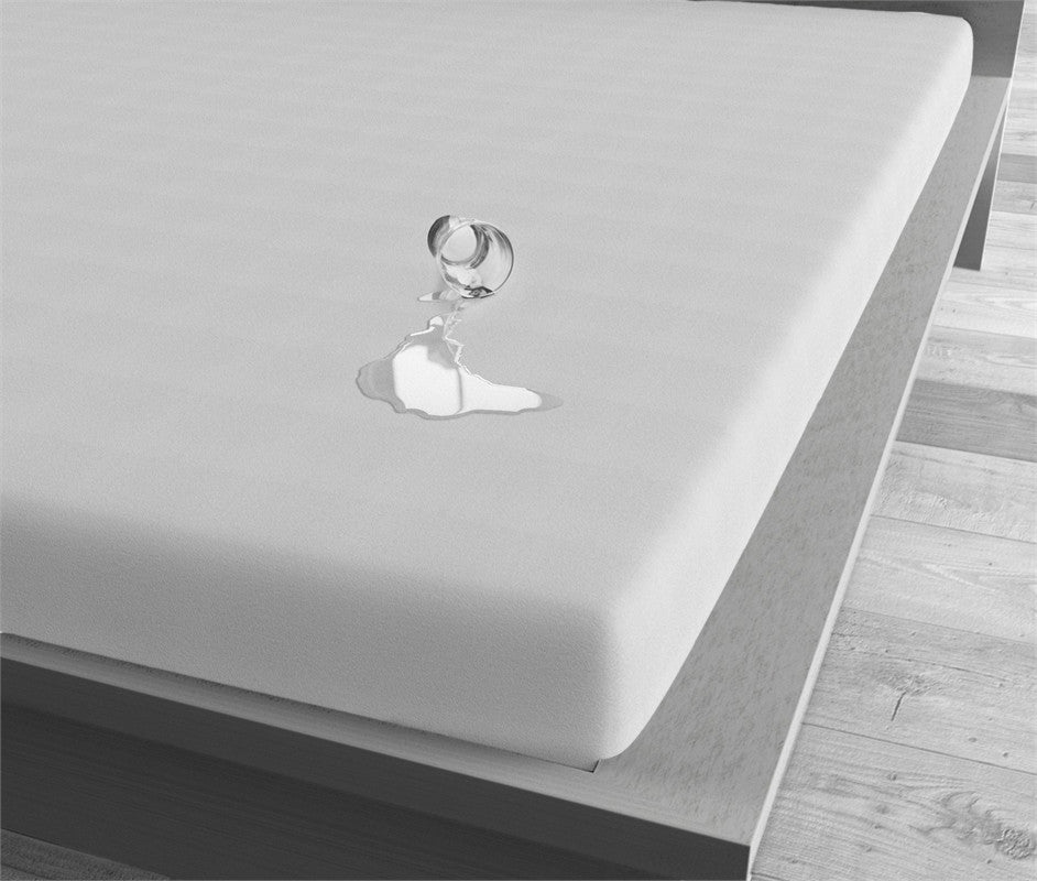 Wit waterdicht hoeslaken op een matras, met omgevallen glas en vloeistof die op het oppervlak blijft liggen