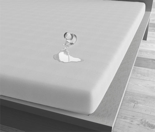 Wit waterdicht hoeslaken op een matras, met omgevallen glas en vloeistof die op het oppervlak blijft liggen