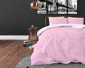 Roze dekbedovertrek met witte binnenkant en roze kussenslopen op een bed met koperkleurig frame in een donkere slaapkamer