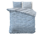 Opgemaakt bed met blauw gewassen flanel dekbedovertrek, omgeslagen lichtgrijze binnenkant en twee bijpassende kussens