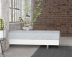 Grijs flanellen hoeslaken op een matras met wit bedframe voor een bakstenen muur