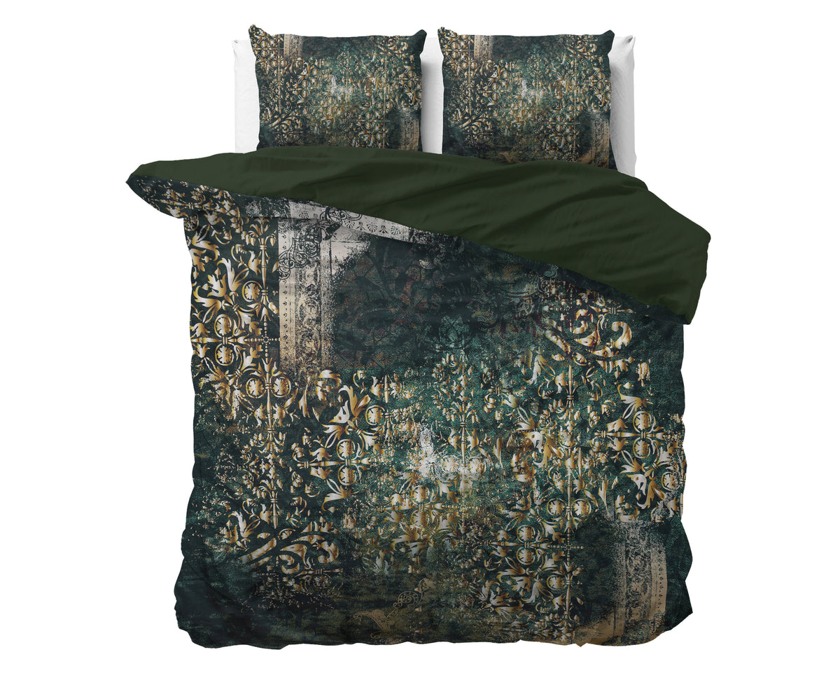 Groen dekbedovertrek met goudkleurig ornamentdessin en twee kussenslopen op een bed, effen groene achterzijde zichtbaar