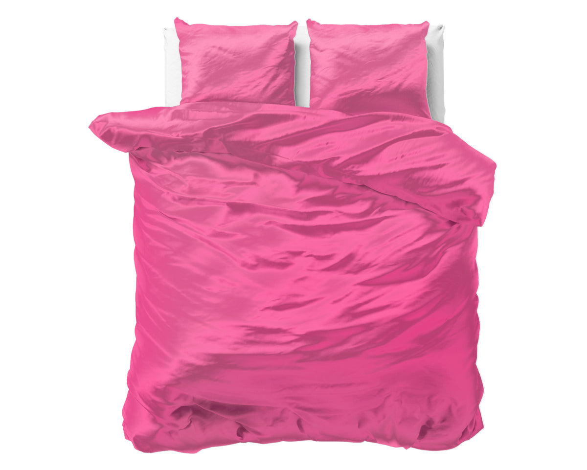 Fel roze satijnen dekbedovertrek met twee bijpassende kussens op een bed, effen en glanzend