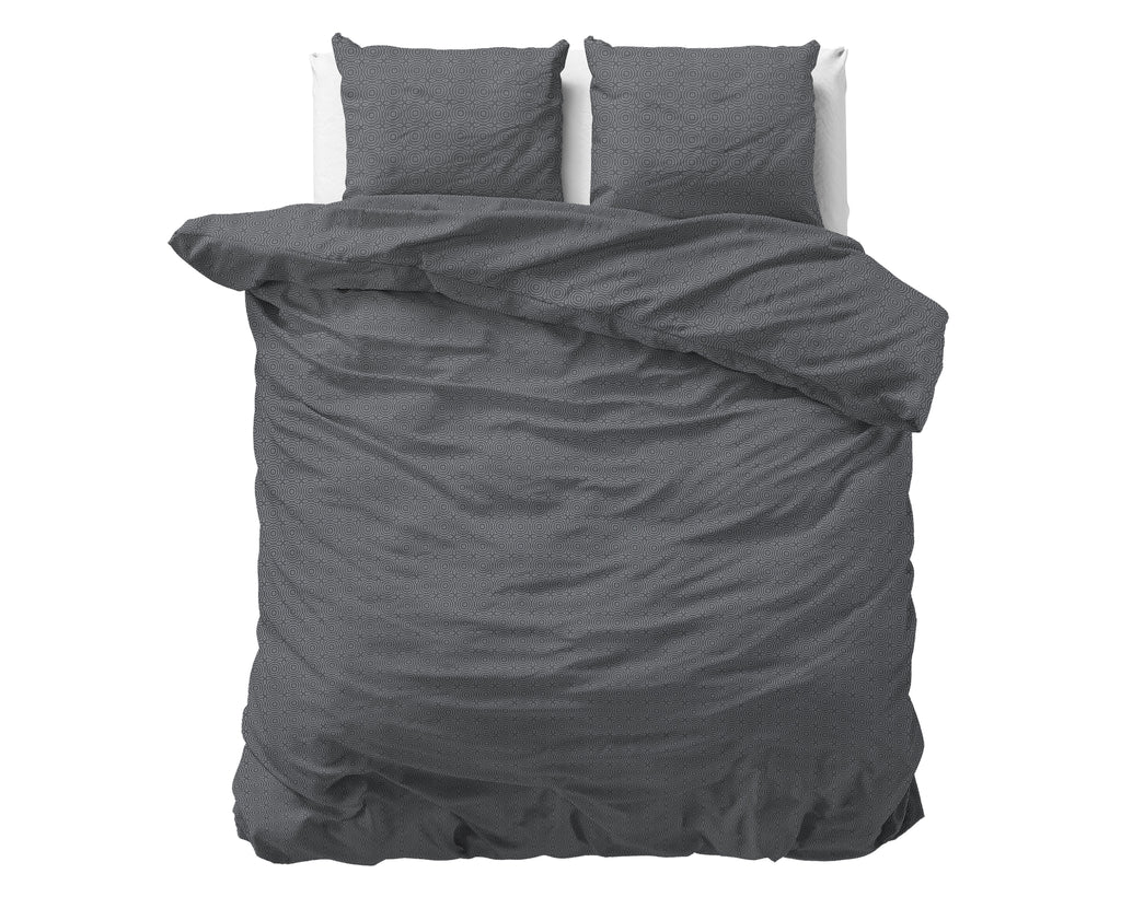 Antraciet dekbedovertrek met subtiel geometrisch dessin en twee bijpassende kussens op een bed