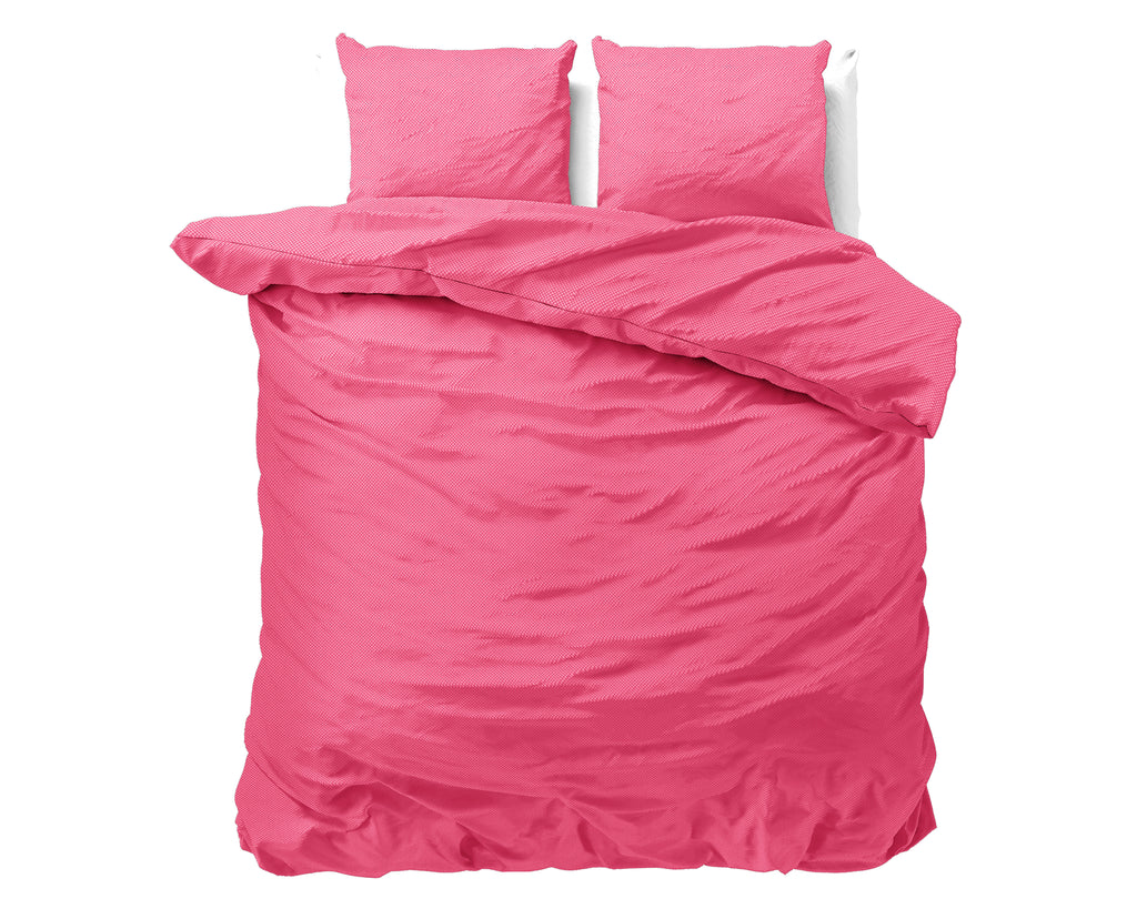 Roze dekbedovertrek met twee bijpassende kussens op een bed, met omgeslagen dekbed
