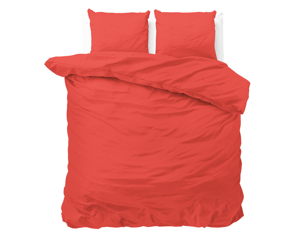 Rood dekbedovertrek met twee bijpassende kussenslopen op een bed, met omgeslagen dekbed tegen een witte achtergrond