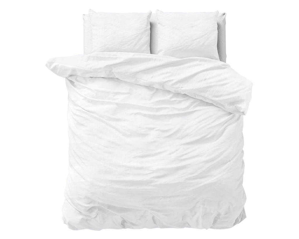Wit stonewashed dekbedovertrek op een bed met witte kussens, gezien van bovenaf