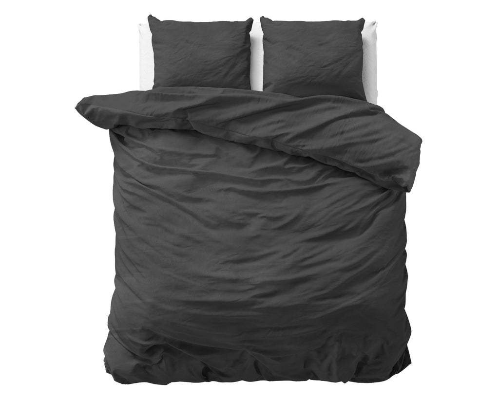 Opgemaakt bed met antraciet stonewashed dekbedovertrek en twee bijpassende kussens tegen een witte achtergrond