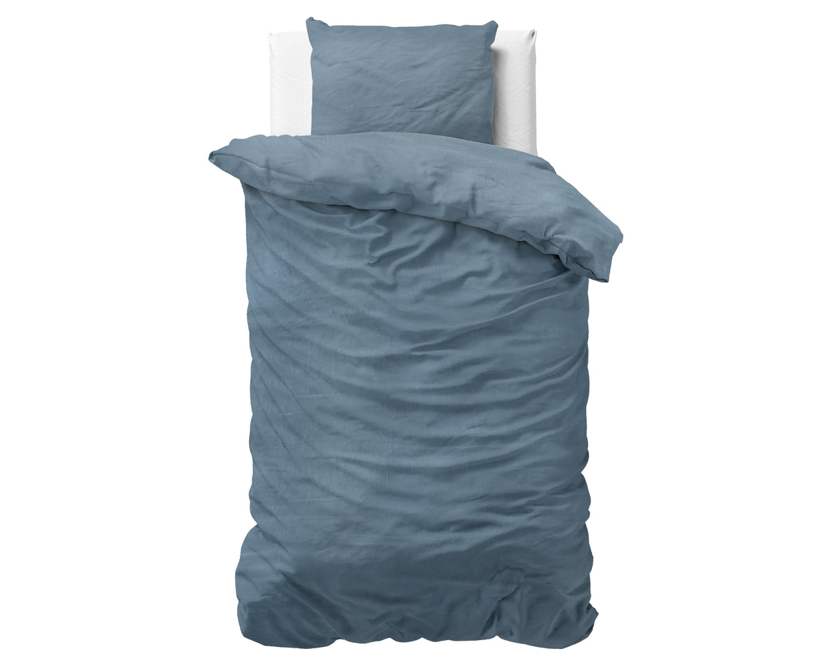 Opgemaakt eenpersoonsbed met blauw stonewashed dekbedovertrek en bijpassende kussensloop, witte achtergrond