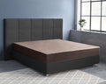 Taupe satijnen hoeslaken op een bed met donkergrijs gestoffeerd hoofdbord en boxspringbasis in een slaapkamer met blauwe muur