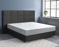 Wit hoeslaken over een matras op een donkergrijs boxspringbed met gecapitonneerd hoofdbord in een blauwgrijze slaapkamer