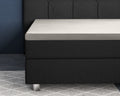Crèmekleurig topper hoeslaken op een boxspring met donkergrijs gestoffeerd hoofdbord