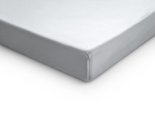 Hoek van een wit satijnen hoeslaken met elastische rand, strak over een matras of topper gespannen