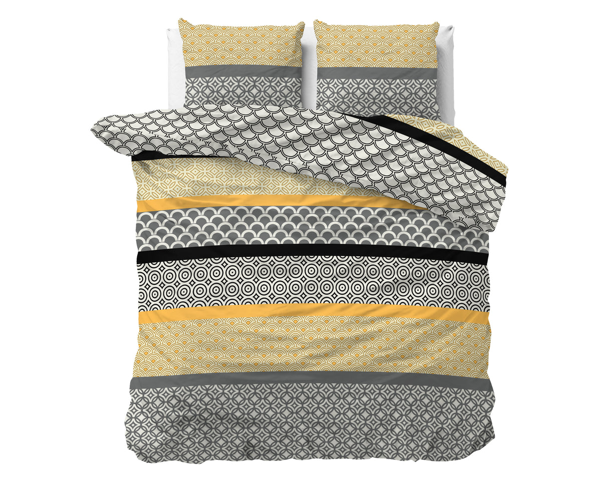 Dekbedovertrek met grafisch dessin in grijs, geel, zwart en off-white, met twee bijpassende kussens op een bed