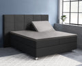 Grijs splittopper hoeslaken op een donkergrijs boxspringbed met hoofdbord, rechterhelft van de topper omhoog verstelbaar