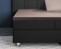 Taupe satijnen hoeslaken over een splittopper op een zwarte boxspring met gecapitonneerd hoofdbord
