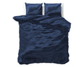 Marineblauw satijnen dekbedovertrek met twee bijpassende kussens op een bed met witte achtergrond