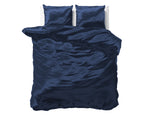 Marineblauw satijnen dekbedovertrek met twee bijpassende kussens op een bed met witte achtergrond