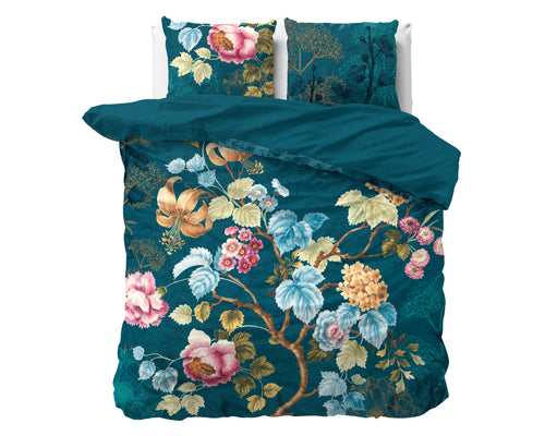 Blauw dekbedovertrek met kleurrijke bloemenprint en twee bijpassende kussens op een bed