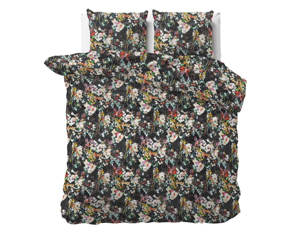 Zwart dekbedovertrek met kleurrijke bloemenprint op een bed, met twee bijpassende kussens