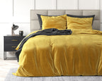 Goudkleurig velvet dekbedovertrek met kussenslopen op een bed met grijs hoofdbord en antracietkleurige plaid