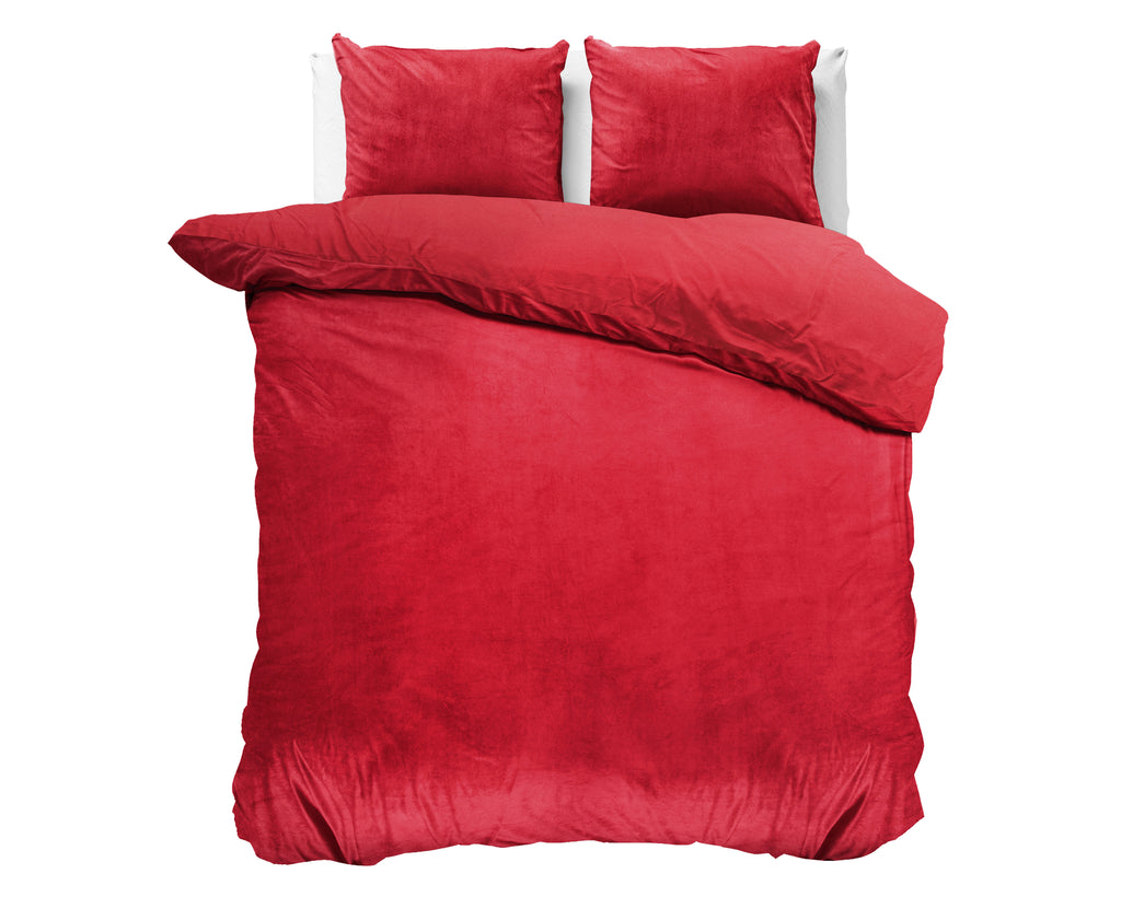 Rood fluwelen dekbedovertrek met twee bijpassende kussenslopen op een bed, voor een witte achtergrond