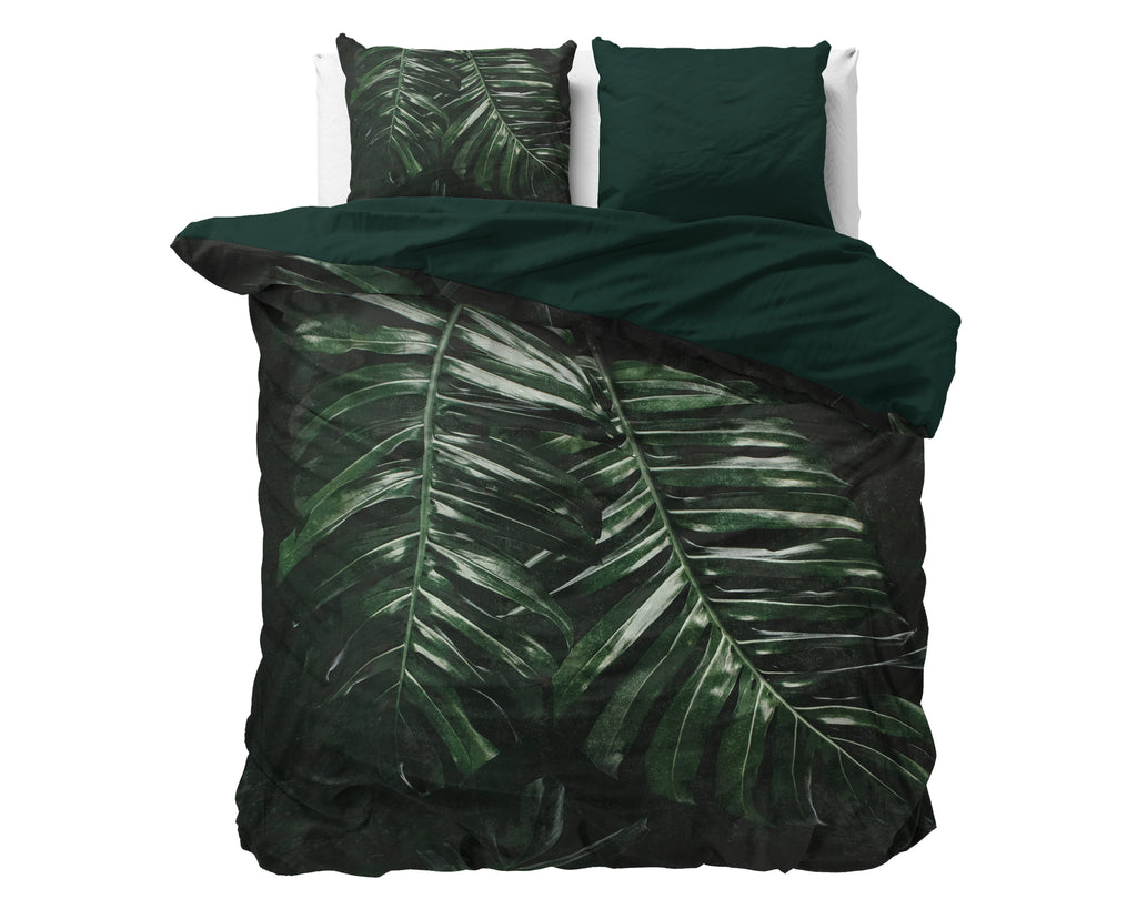 Groen dekbedovertrek met donkere bladprint en effen groene keerzijde, met twee kussenslopen op een bed