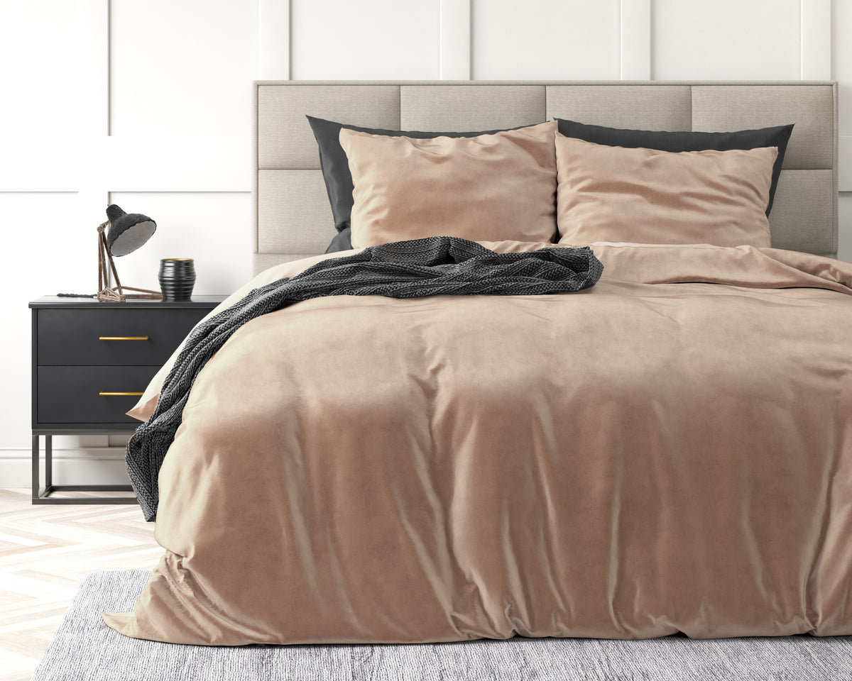 Huidskleurig velvet dekbedovertrek met twee kussens op een bed met beige gestoffeerd hoofdbord en zwart nachtkastje