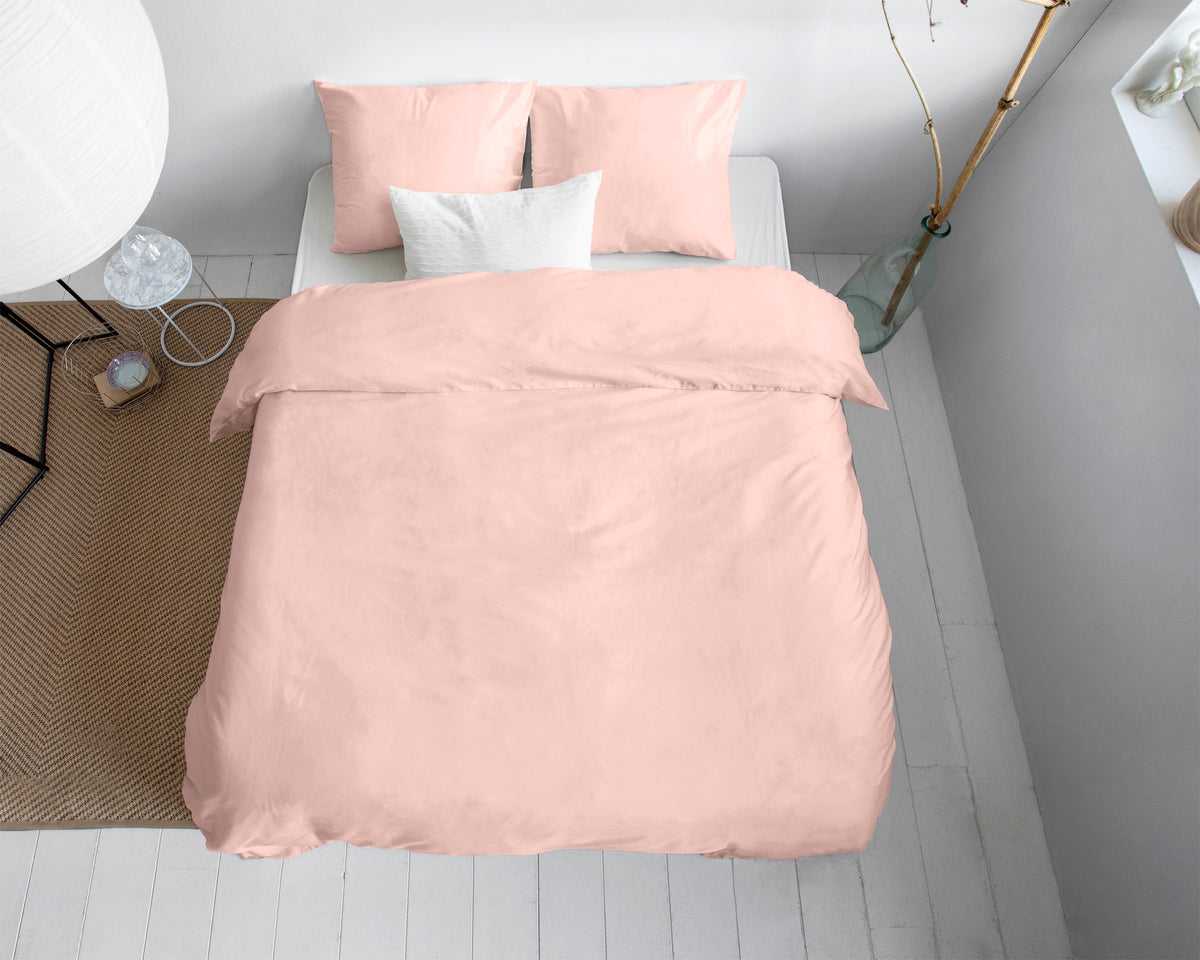 Roze effen dekbedovertrek met twee roze kussenslopen op een bed, gezien van boven