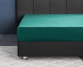 Donkergroen hoeslaken van katoensatijn om een matras op een antracietkleurig boxspringbed