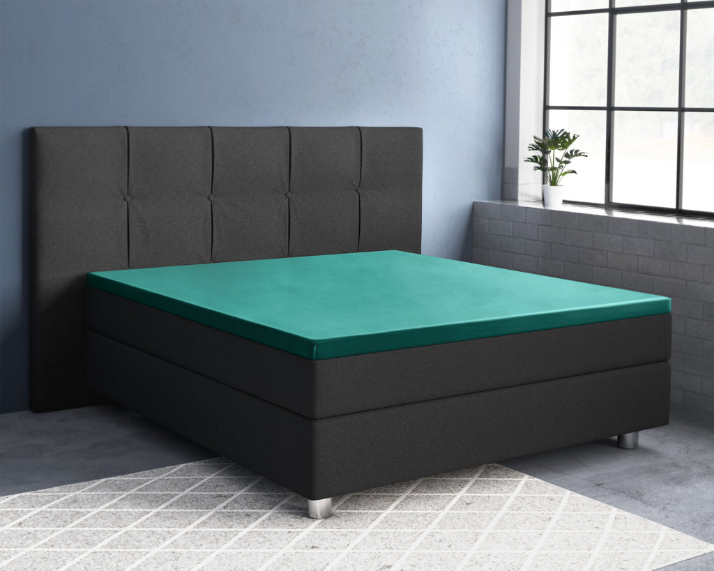 Donkergroen satijnen topper hoeslaken op een antracietkleurig boxspringbed met gecapitonneerd hoofdbord in een slaapkamer