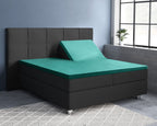Groen splittopper hoeslaken op een donkergrijs boxspringbed, met één hoofdeinde omhoog gezet