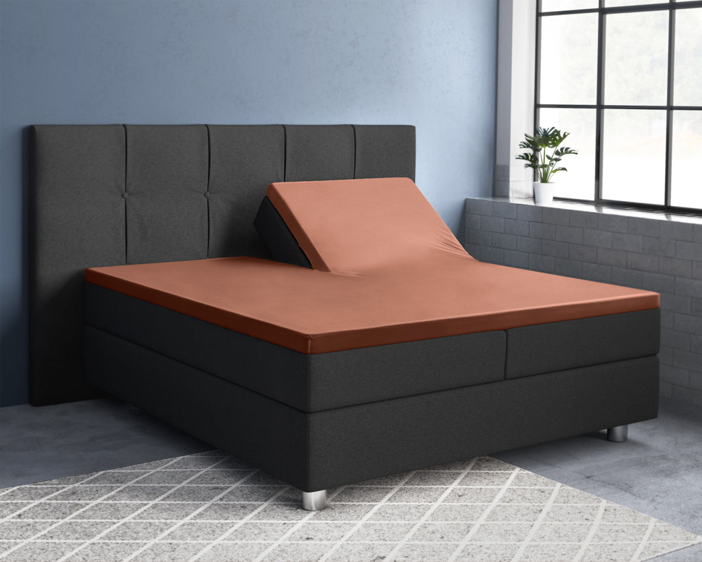 Bruin splittopper hoeslaken op een antracietkleurig boxspringbed, de ene bedhelft omhoog gezet