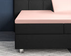 Roze satijnen splittopper hoeslaken op een zwarte boxspring met verstelbaar hoofdeinde