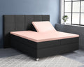 Roze splittopper hoeslaken op een antracietkleurige boxspring met gedeeltelijk omhooggezet hoofdeinde