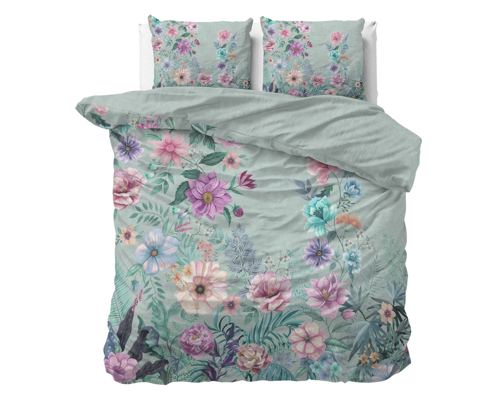 Dekbedovertrek Flore met kleurrijke bloemenprint op blauwgroene ondergrond, met twee bijpassende kussenslopen op een bed