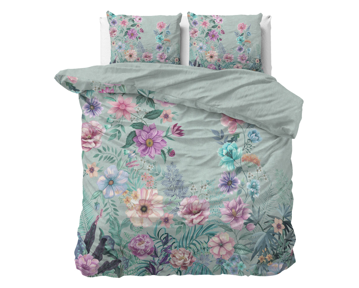 Dekbedovertrek Flore met kleurrijke bloemenprint op blauwgroene ondergrond, met twee bijpassende kussenslopen op een bed