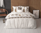 Bed met wit-beige dekbedovertrek met verenprint en kussens voor een houten lamellenwand